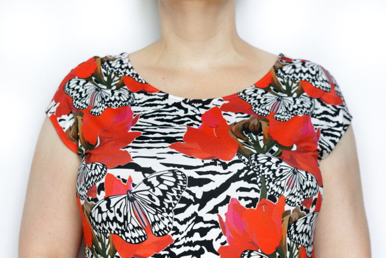 Biustonosz SMN Fetysz Czarny Ewa Michalak na biuście autorki Stanikomanii - widok z przodu w ubraniu (letnia sukienka w czerwone kwiaty)